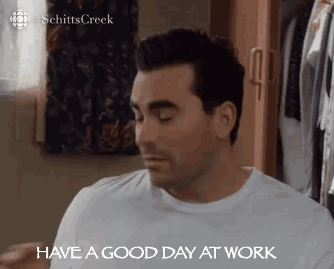 a man in a white shirt is saying `` have a good day at work '' while sitting in front of a closet .