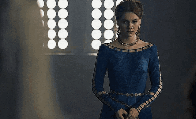 a woman in a blue dress is standing in a dark room .
