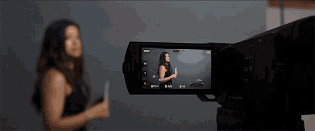 a woman stands in front of a camera that says ' nikon ' on it