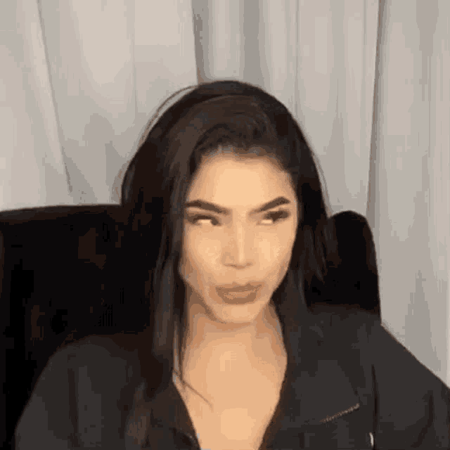 a woman is sitting in a chair with her eyes closed and making a funny face .