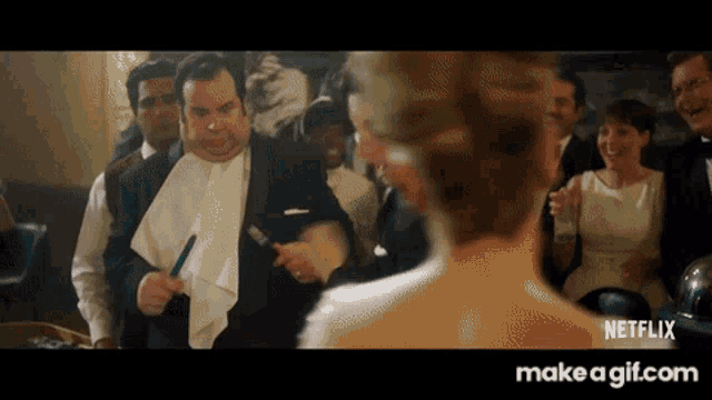 a man in a tuxedo is holding a toothbrush in front of a woman in a white dress