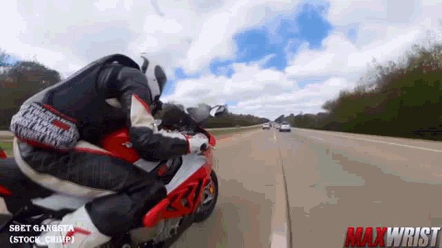 a man riding a red and white motorcycle on a highway with the words maxwrist on the bottom