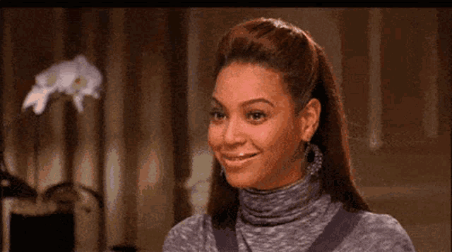 a woman wearing a turtleneck sweater is smiling .