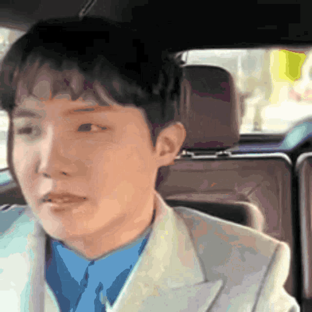 a man in a suit and blue shirt is sitting in a car