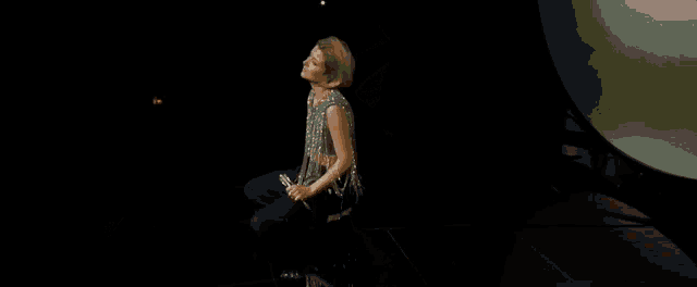 a woman is kneeling down on a stage with a microphone