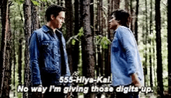 two men are standing in the woods and one of them is giving the other a thumbs up