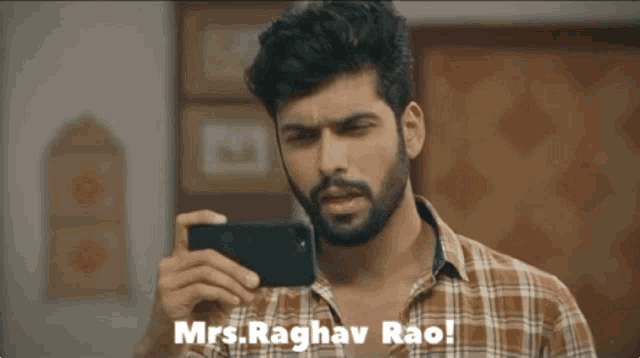 a man in a plaid shirt is taking a picture of himself with the words mrs. raghav rao below him