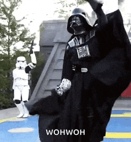 a person dressed as darth vader is dancing with stormtroopers .