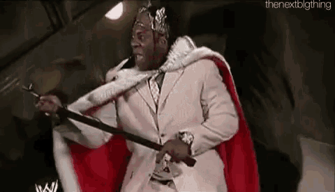 a man in a suit and crown is holding a sword and a cane .