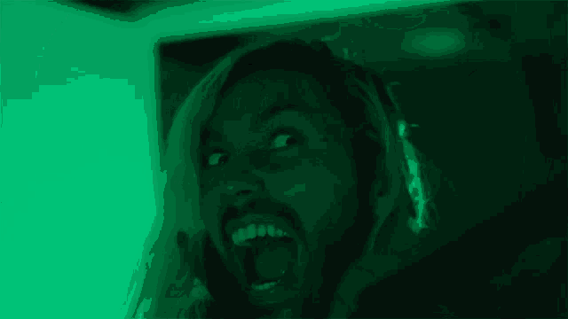 a man with a beard is making a funny face in a green light