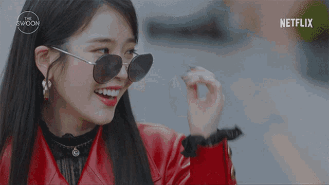 a woman wearing sunglasses and a red jacket with a netflix logo on the bottom
