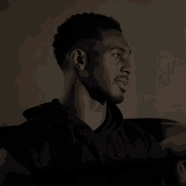 a man wearing a black hoodie looks to his right