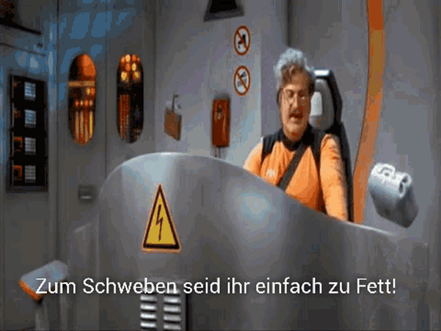 a man in an orange shirt is sitting in front of a sign that says zum schweben sed ihr einfach zu fett
