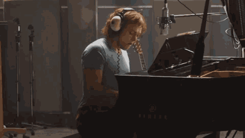 a man wearing headphones is playing a piano that says yamaha on it