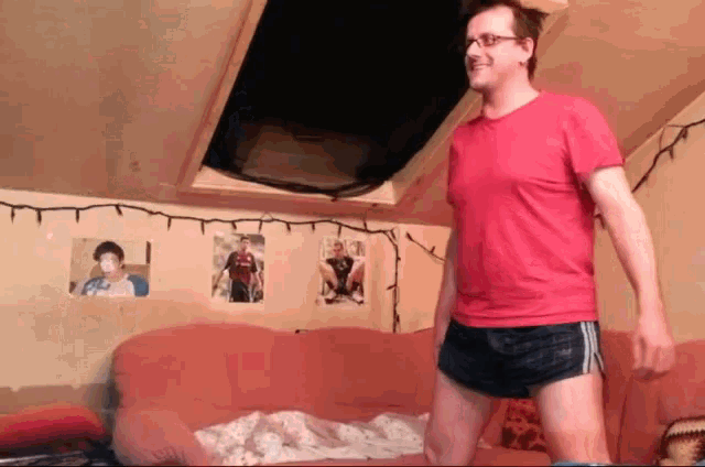 a man in a red shirt and black shorts stands in front of a couch