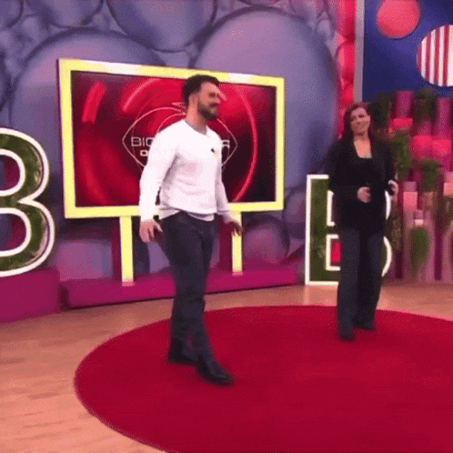 a man and a woman are dancing on a red carpet in front of a big screen with the number 3 on it