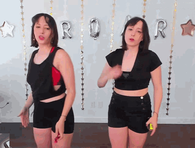 two women are dancing in front of a roar balloon