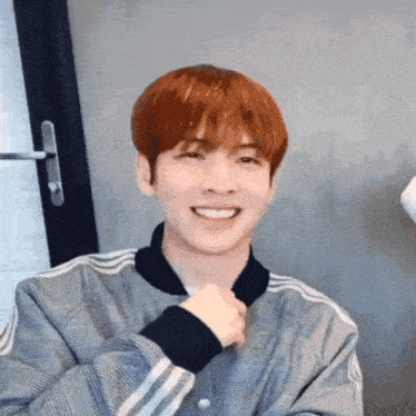 a young man with red hair is wearing a plaid jacket and smiling .