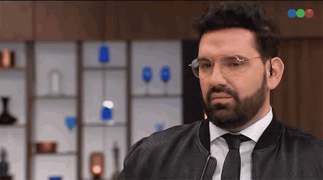 a man with glasses and a beard is wearing a black leather jacket