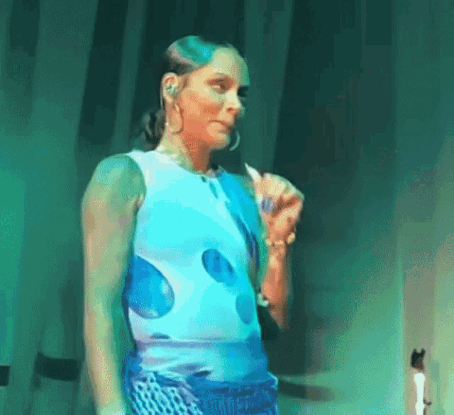 a woman in a blue and white dress is dancing on a stage in front of a green background .