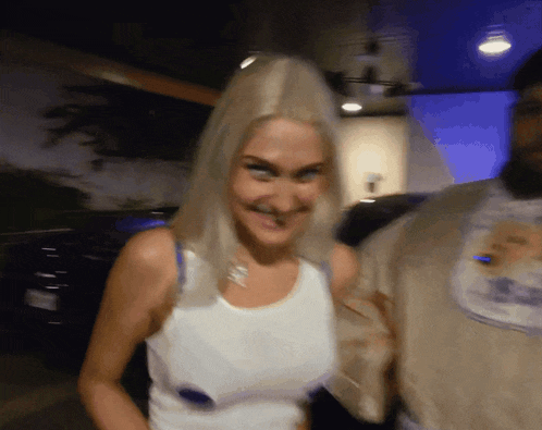 a woman with blonde hair wearing a white tank top