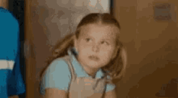 a little girl is saying `` cry me a river '' while sitting in front of a wall .