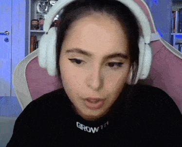 a woman wearing headphones is sitting in a pink chair and making a funny face .