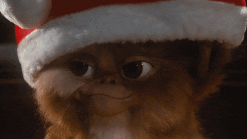 a gremlin wearing a santa hat looks at the camera