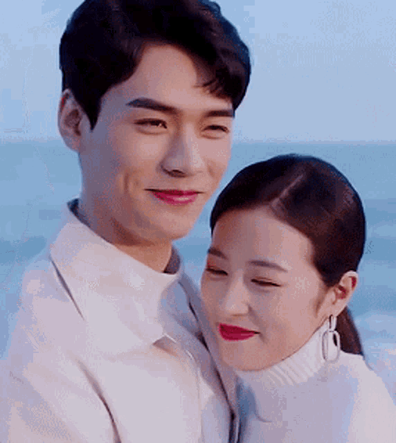 a man and woman are standing next to each other on the beach .