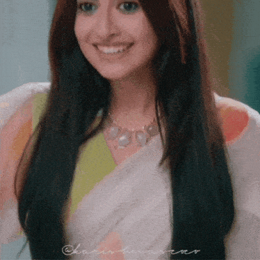 a woman wearing a white saree and a necklace smiles