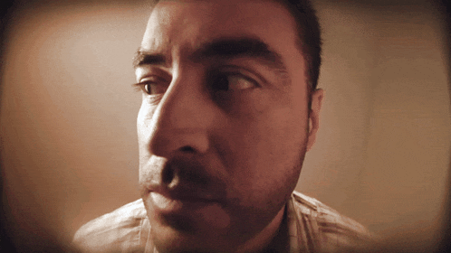 a man with a beard looks at the camera with a serious look on his face