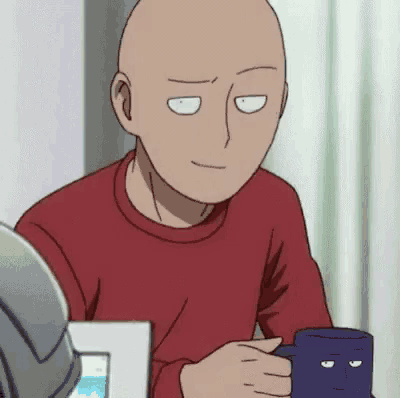 a bald man is sitting at a table with a cup of coffee in his hand .