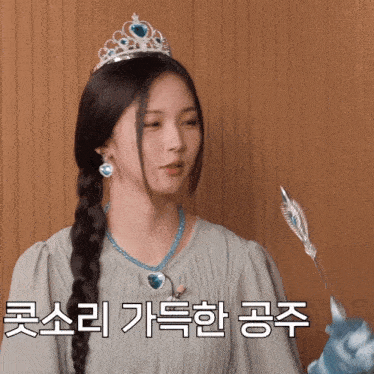 a girl wearing a tiara and holding a wand with korean writing on it