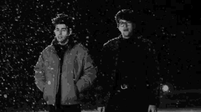 a black and white photo of two men in the snow