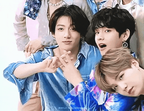 a group of young men are standing next to each other and making a heart with their hands .