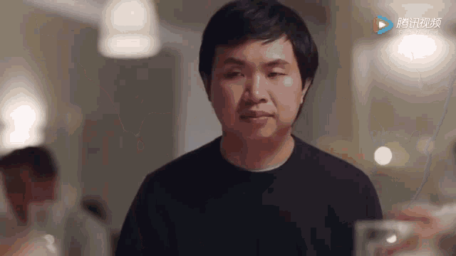 a man in a black sweater is holding a glass in his hand .