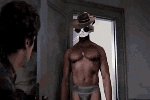 a shirtless man in underwear and a cowboy hat stands in a doorway