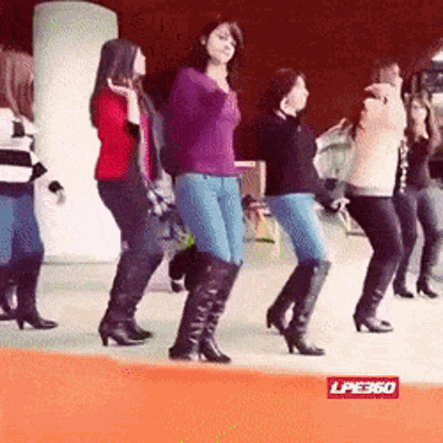 a group of women are dancing in front of a sign that says lpe360 on it