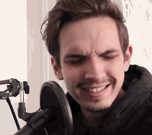 a man is smiling in front of a microphone and making a funny face