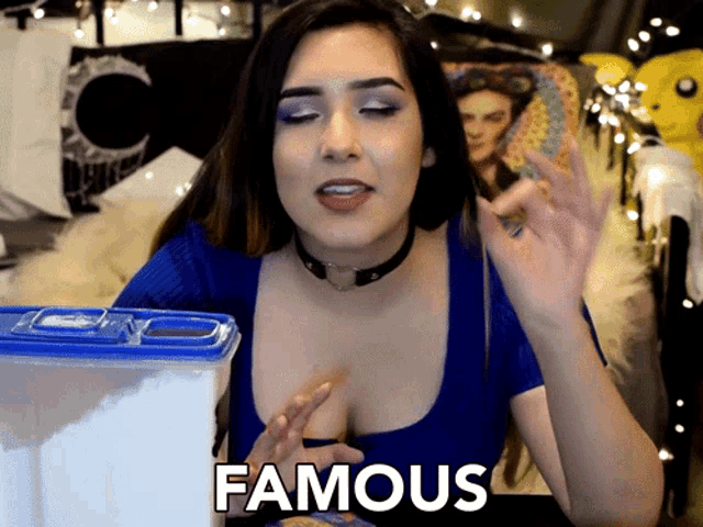 a woman in a blue top says famous in front of a blue container
