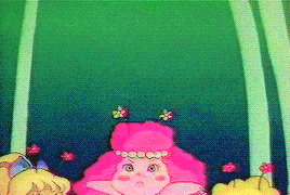 a pink cartoon character with flowers in her hair is standing in front of a green background