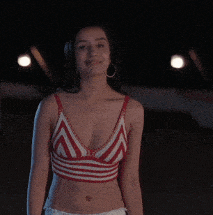 a woman in a red and white striped crop top and white shorts is smiling .
