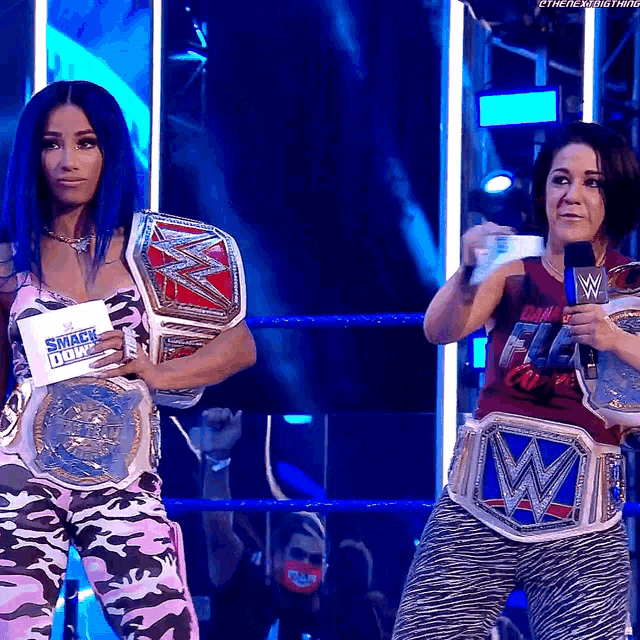 two women are standing in a wrestling ring with their smack down belts on
