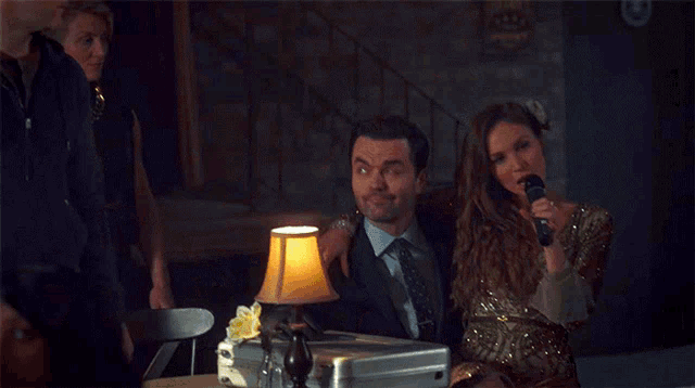 a woman singing into a microphone next to a man with the words girls are like below her