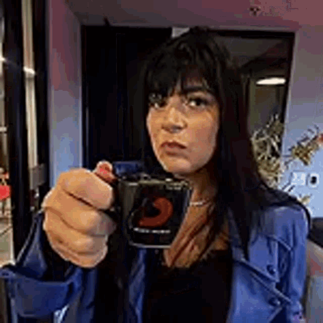 a woman is holding a cup of coffee in her hand .