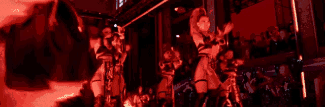 a woman in a pink wig is dancing on a stage in front of a purple light .