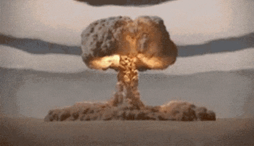a nuclear explosion in the middle of a desert with mountains in the background .