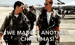 two men in military uniforms are standing next to each other on a runway with the words `` we made it another christmas '' .