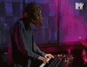 a man is playing a keyboard with a mtv logo behind him