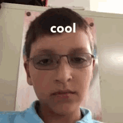 a young boy wearing glasses and a blue shirt is making a funny face with the word cool on his forehead .